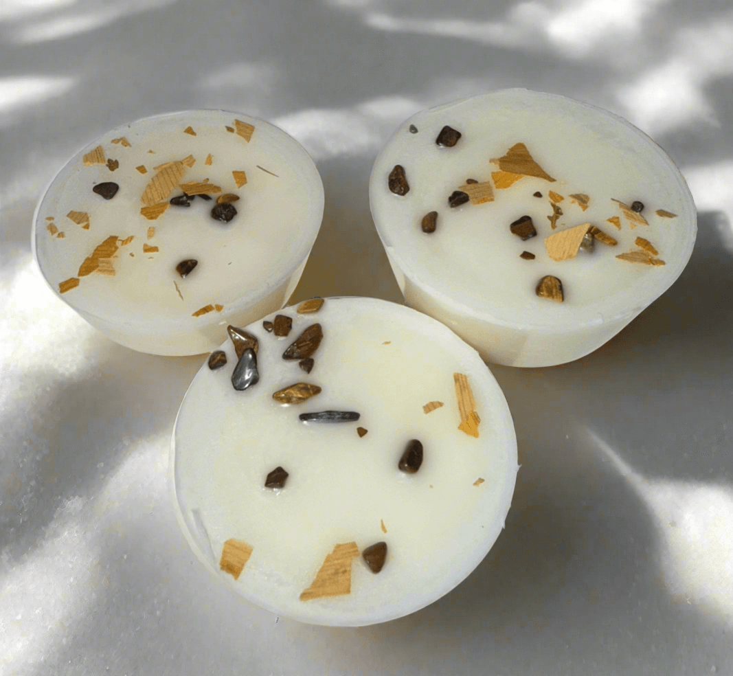 Three artisan wax melts with a blend of herbs and crystals, featuring white wax and natural embellishments.