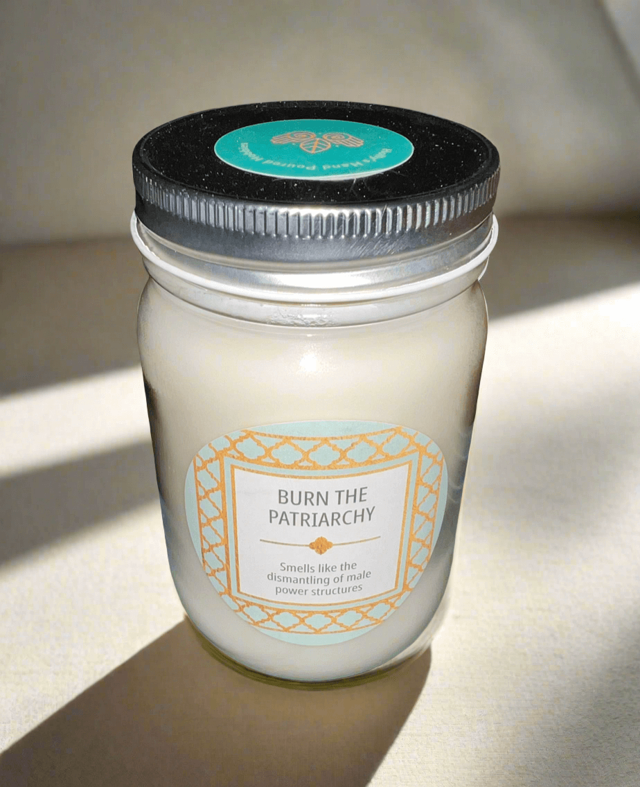 14 oz Burn the Patriarchy scented soy candle in a glass jar with decorative label, infused with crystals.
