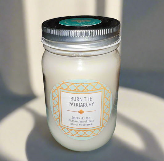 14 oz Burn the Patriarchy scented soy candle in glass jar with gold and turquoise decal, promoting feminist themes.